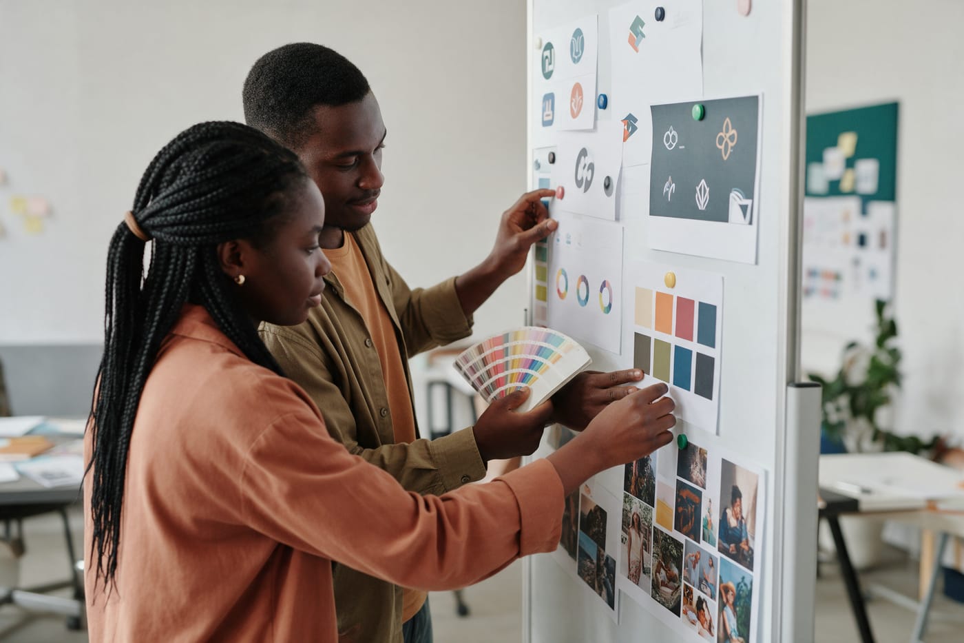 Two learners arranging logo ideas and colour palettes on a mood board